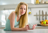 Portrait of sleepy young woman with cup of coffee in kitchen