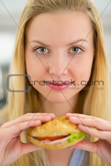 Portrait of young woman holding sandwich