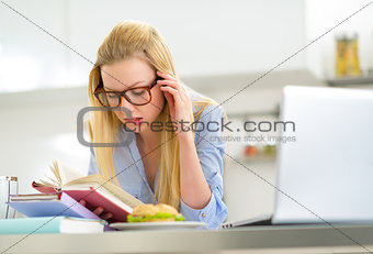 Young woman studying in kitchen