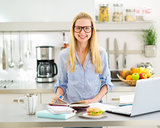 Portrait of happy young woman studying in kitchen