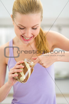 Happy young woman eating chocolate cream from jar