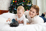 Young Caucasian mother and toddler son playing with RC controller against decorated Christmas tree