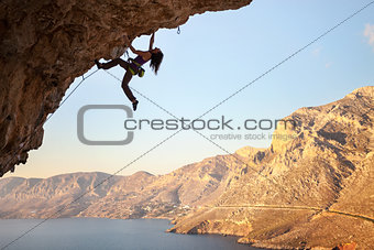 Female rock climber on overhanging cliff, Kalymnos Island