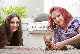 couple of young women playing with a small dog