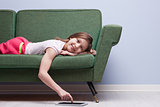 little girl using a tablet relaxed on a sofa