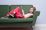 little girl enjoying a tablet on her sofa