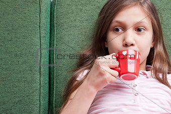 young little girl drinking from a small red cup
