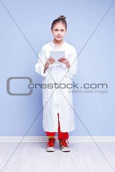 little scientist girl in a smock with a digital tablet