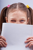 little girl winking behind a squared exercise book