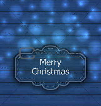 Christmas label on wooden texture with light