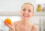 Portrait of happy young woman holding orange