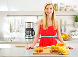 Portrait of happy young woman cutting fruits in kitchen