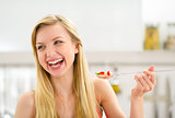 Portrait of happy young woman eating fruits salad