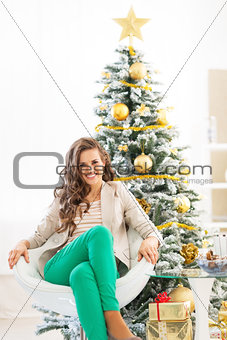 Portrait of smiling young woman sitting near christmas tree