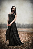 Beautiful sad goth girl holds black umbrella. Grunge texture effect