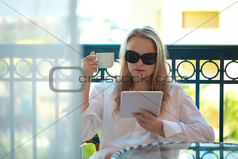 Woman sitting reading a tablet-pc on balcony