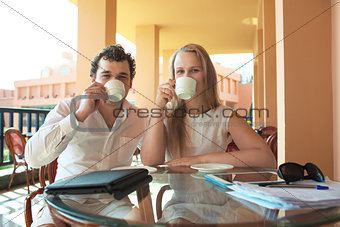 Young couple drinking coffee on a balcony