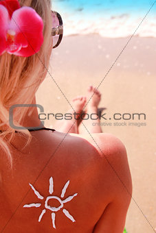 sun cream on the female back on the seaside