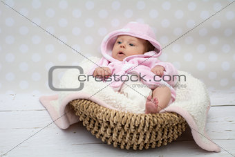 cute baby girl sitting in a basket 