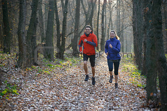 Young Couple Running on the Trail in the Wild Forest