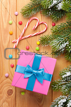 Gift box over christmas wooden background with snow fir tree