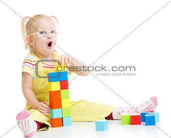 Funny kid in eyeglases making tower using blocks with letters isolated