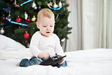 Toddler boy holding RC controller while sitting on bed at home at christmas time