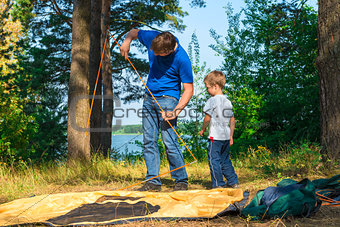 father and son set the tent on the lake
