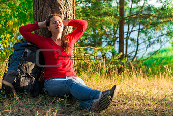 strongly weary backpacker resting against a tree