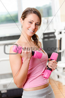 Smiling young woman weightlifting at the gym