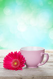 Cup of coffee and gerbera on wooden table