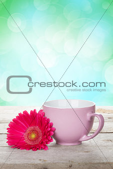 Cup of coffee and gerbera on wooden table