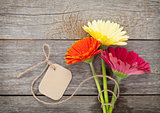 Three colorful gerbera flowers with tag
