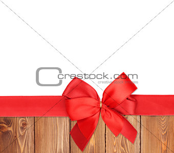 Red ribbon with bow over wood background