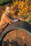 Portrait of smiling young woman near wooden barrel in autumn out