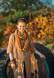 Portrait of smiling young woman standing near wooden barrel in a