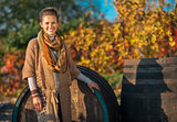 Portrait of happy young woman standing near wooden barrel in aut