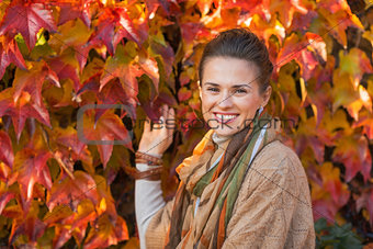 Portrait of happy young woman in front of autumn foliage