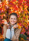 Portrait of smiling young woman in front of autumn foliage