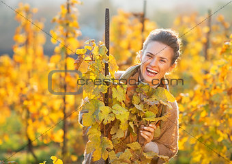 Portrait of happy young woman in autumn vineyard looking out fro