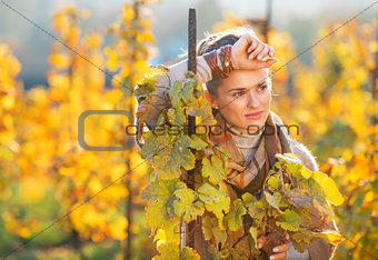 Portrait of thoughtful young woman standing in autumn vineyard