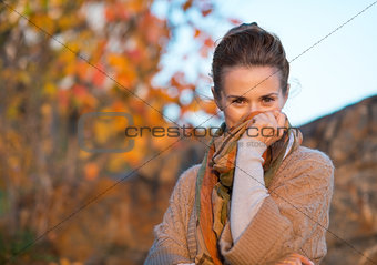 Young woman hiding in scarf in autumn evening