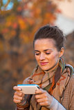Portrait of young woman in autumn evening outdoors writing sms