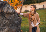Portrait of happy young woman standing in autumn park in evening