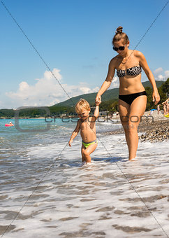 Mum with kid go near sea edge