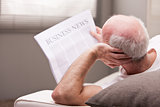 man reading a newspaper on a sofa