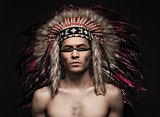 Portrait of the indian strong man posing with traditional native american make up