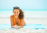 Smiling young woman laying on beach
