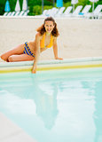 Smiling young woman sitting at poolside