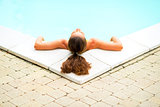 Relaxed young woman laying in pool. rear view